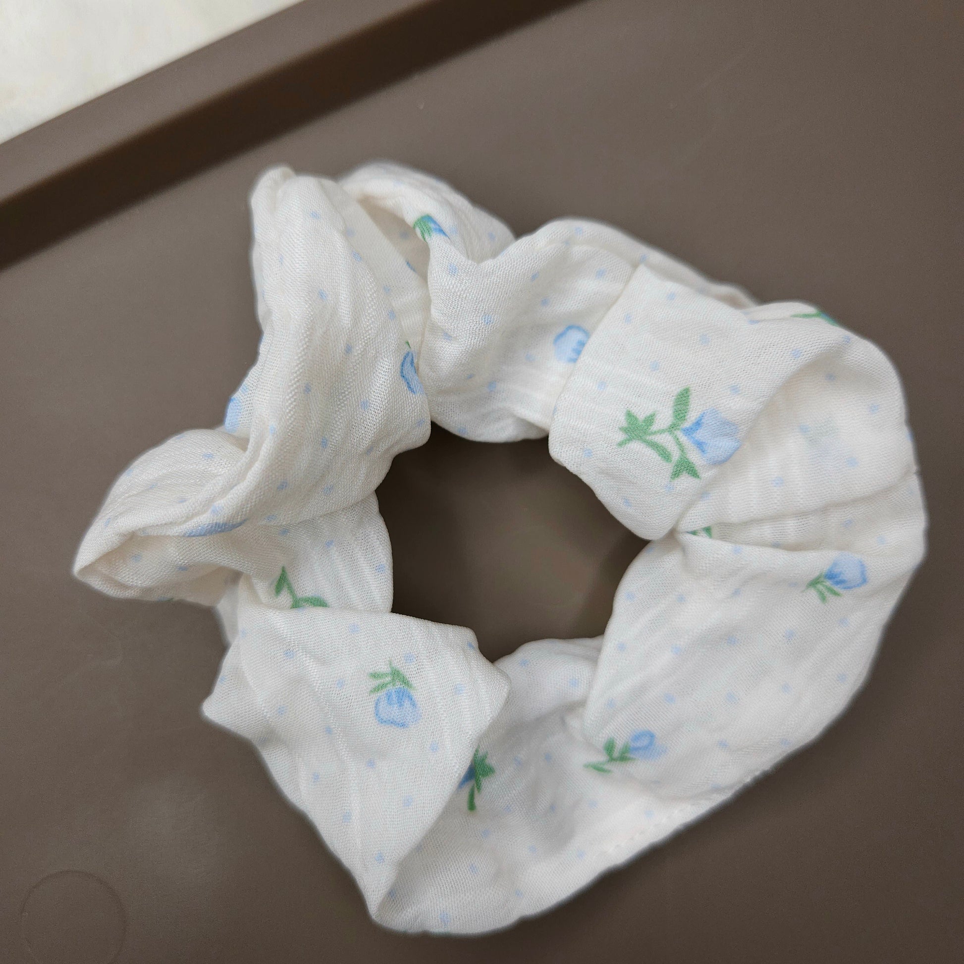 A white scrunchie with sky blue flowers and floral details.