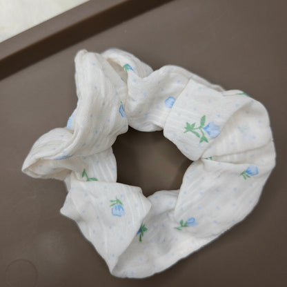 A white scrunchie with sky blue flowers and floral details.