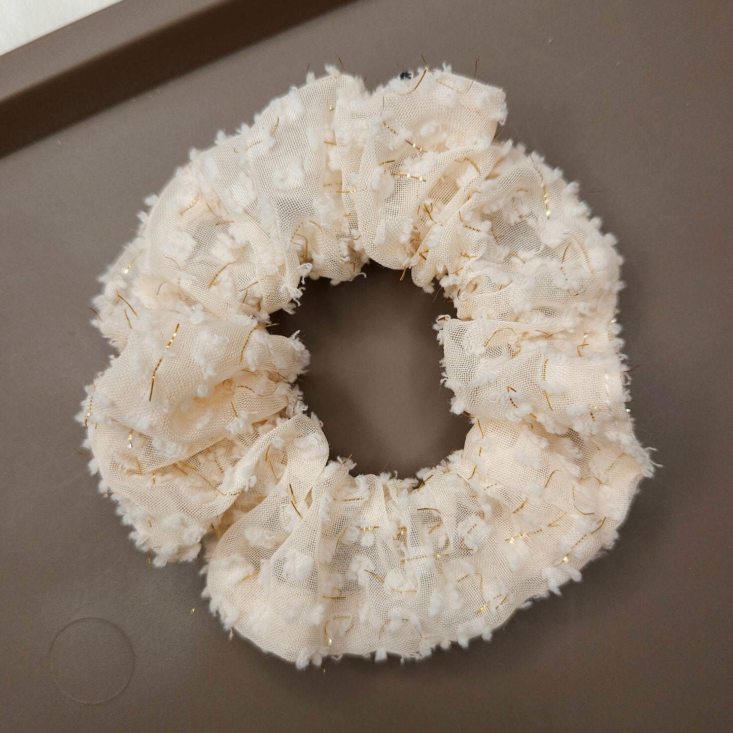 White textured scrunchie on a brown surface