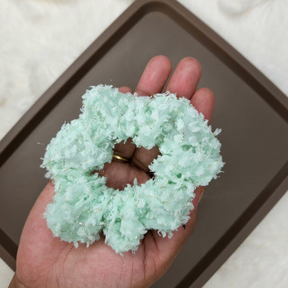 Light green scrunchie held in a hand with a baking tray in the background