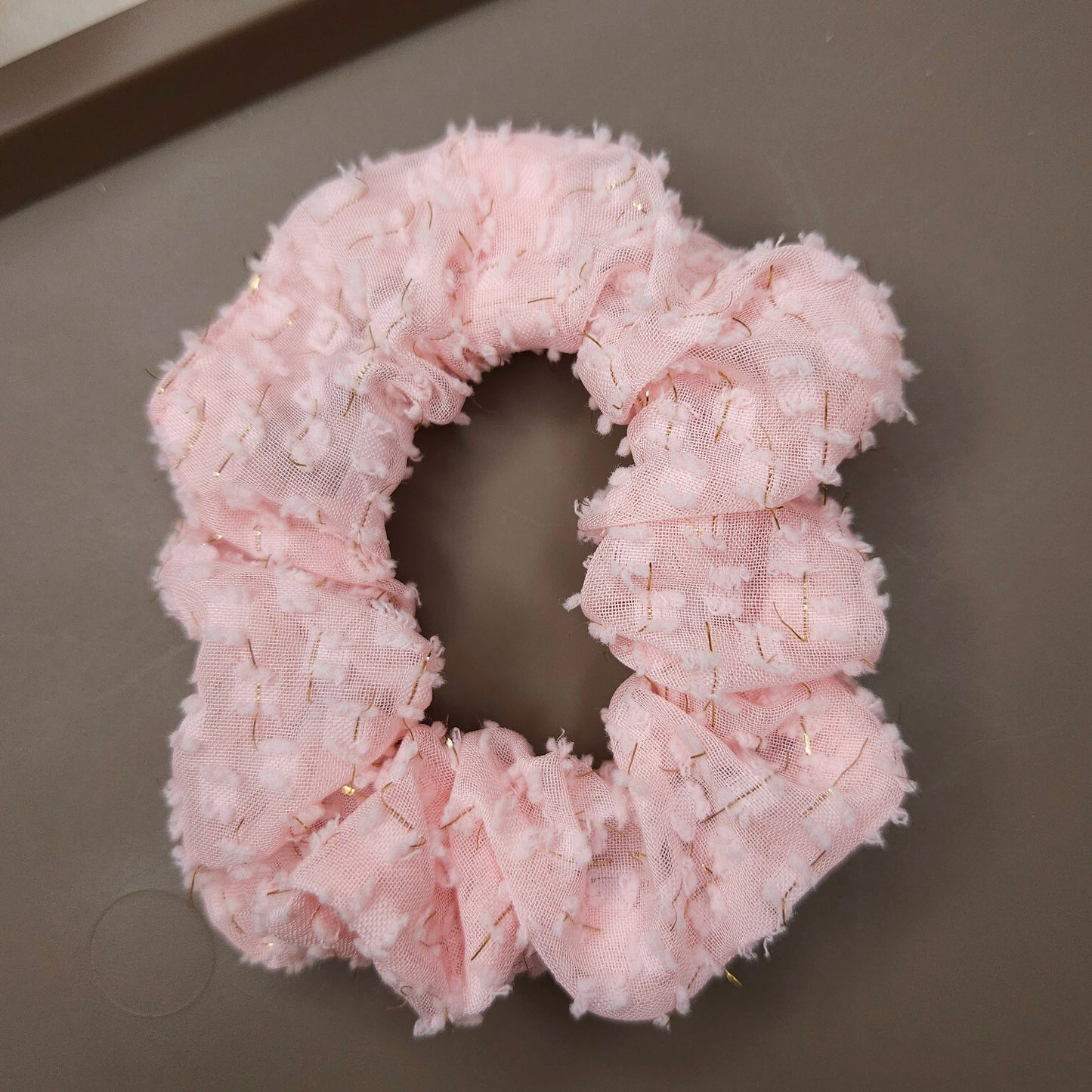 Pink textured scrunchie on a gray surface