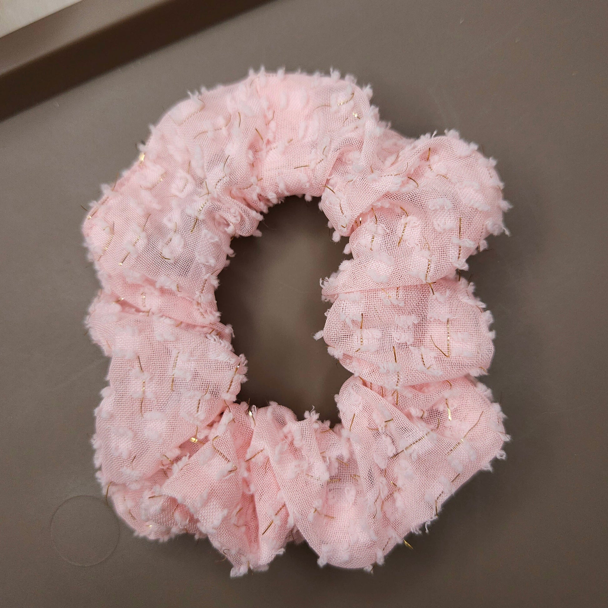 Pink textured scrunchie on a gray surface