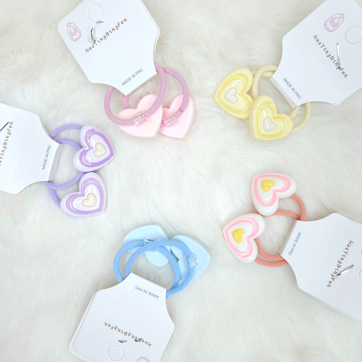 Pastel-colored heart-shaped hair ties with tags on a light background