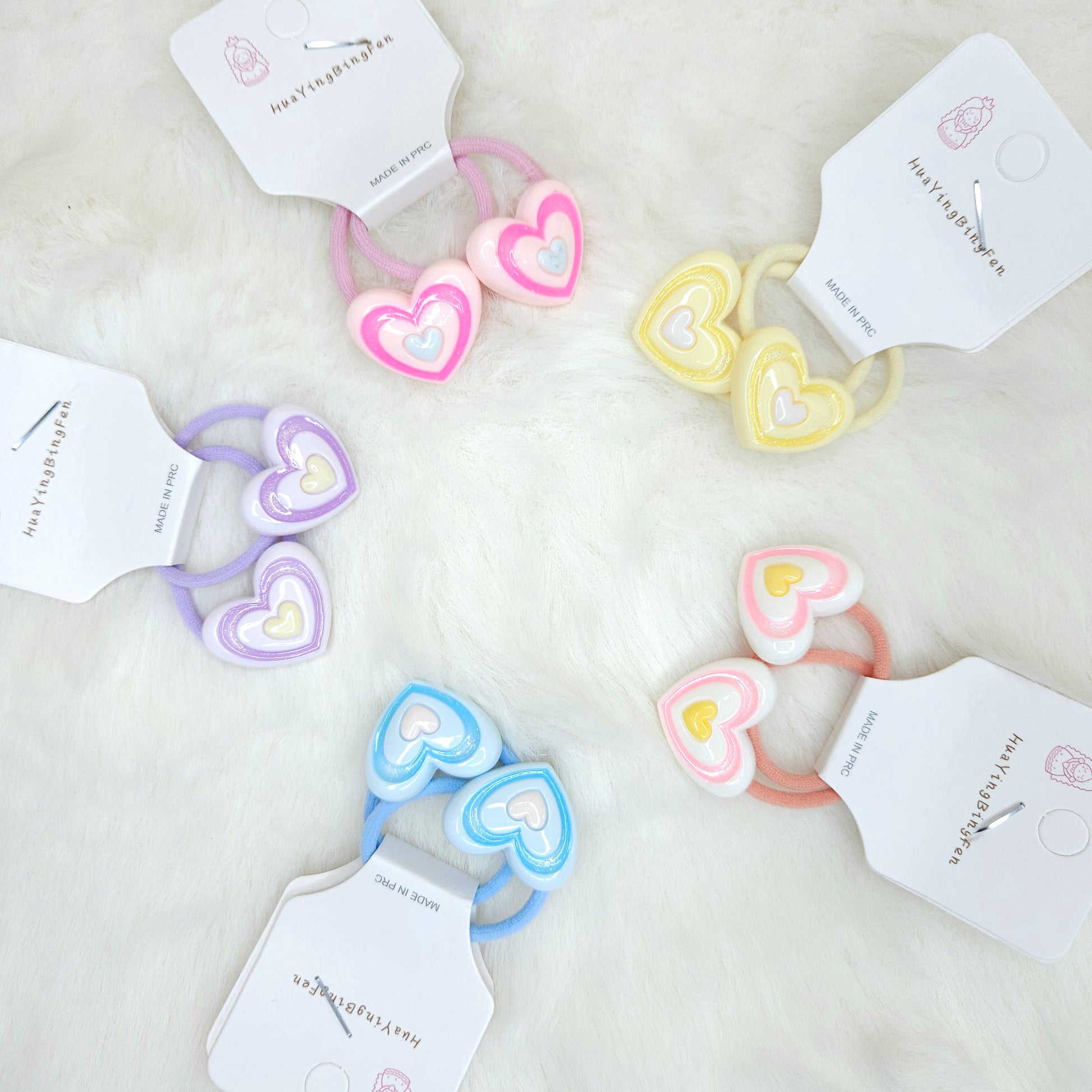 Heart-shaped hair ties in pastel colors with visible brand tags on a white background