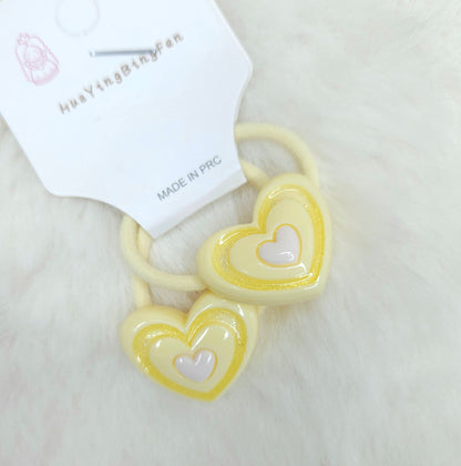 Heart-shaped hair ties with a visible brand label on a light background