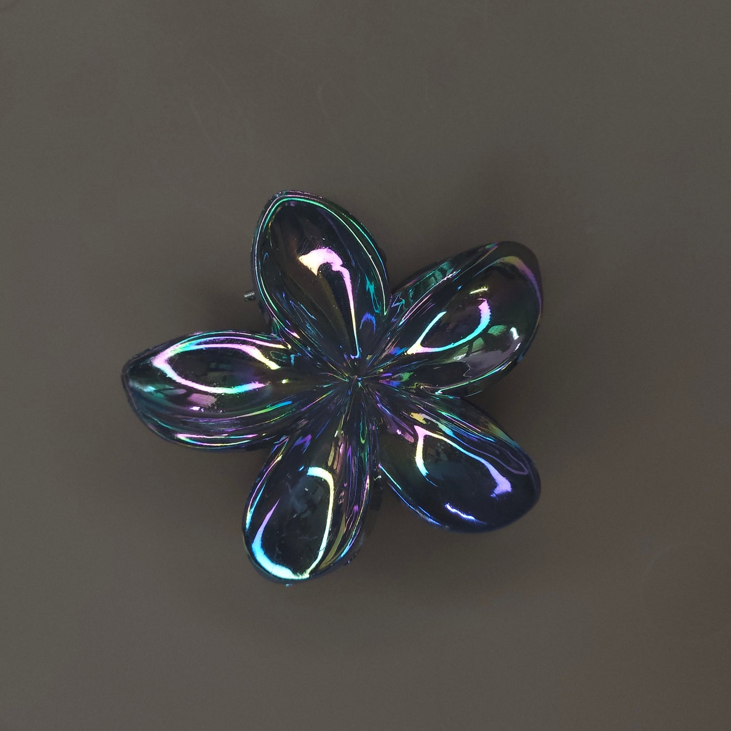 Close-up of a medium, shiny black flower-shaped hair claw clip, featuring a high-shine 'glimmer' finish and strong teeth for an updo.