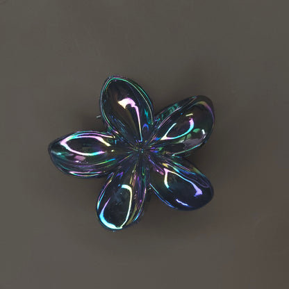 Close-up of a medium, shiny black flower-shaped hair claw clip, featuring a high-shine 'glimmer' finish and strong teeth for an updo.