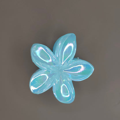 A medium-sized hair claw clip in the shape of a blooming flower, made from a lustrous sky-bluematerial that subtly shimmers in the light.