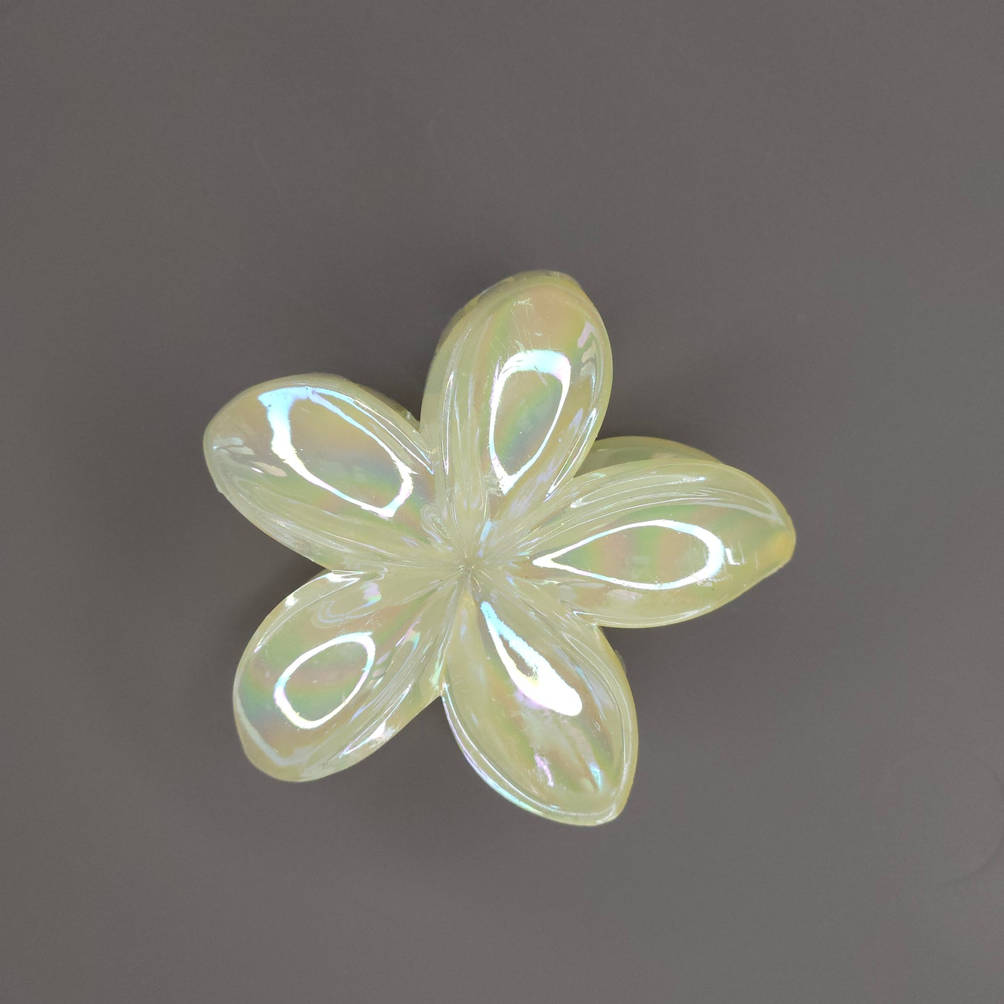 A medium-sized hair claw clip in the shape of a blooming flower, made from a lustrous yellow material that subtly shimmers in the light.