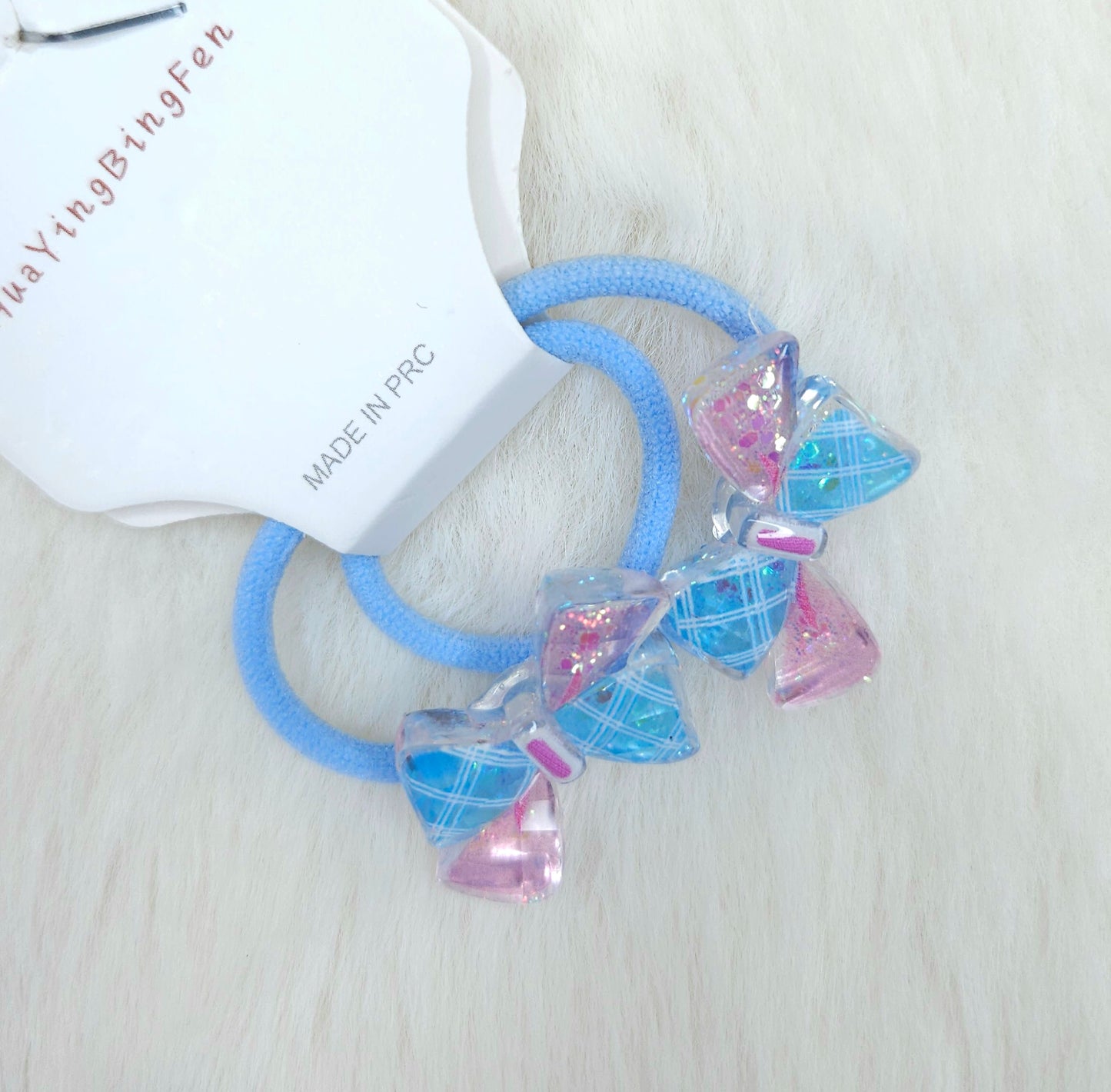 Blue hair ties with pink and clear diamond-shaped beads on a white background