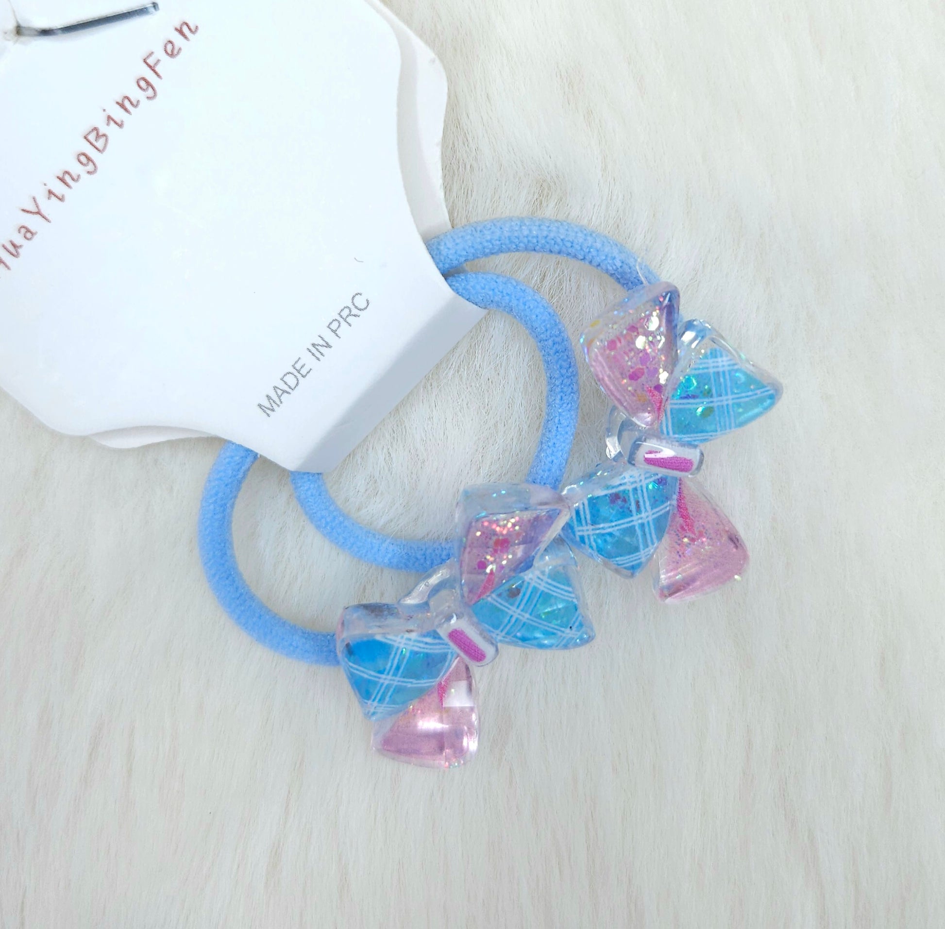 Blue hair ties with pink and clear diamond-shaped beads on a white background