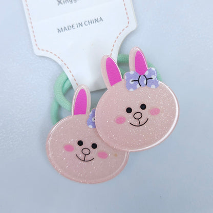 Two pink bunny-shaped hair ties with smiling faces on a light blue background.