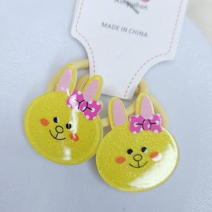Two yellow bunny-shaped hair ties with pink bows on a white background