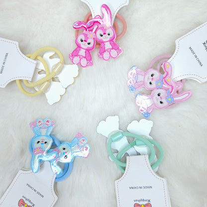 Set of colorful bunny-shaped hair ties with tags on a light background