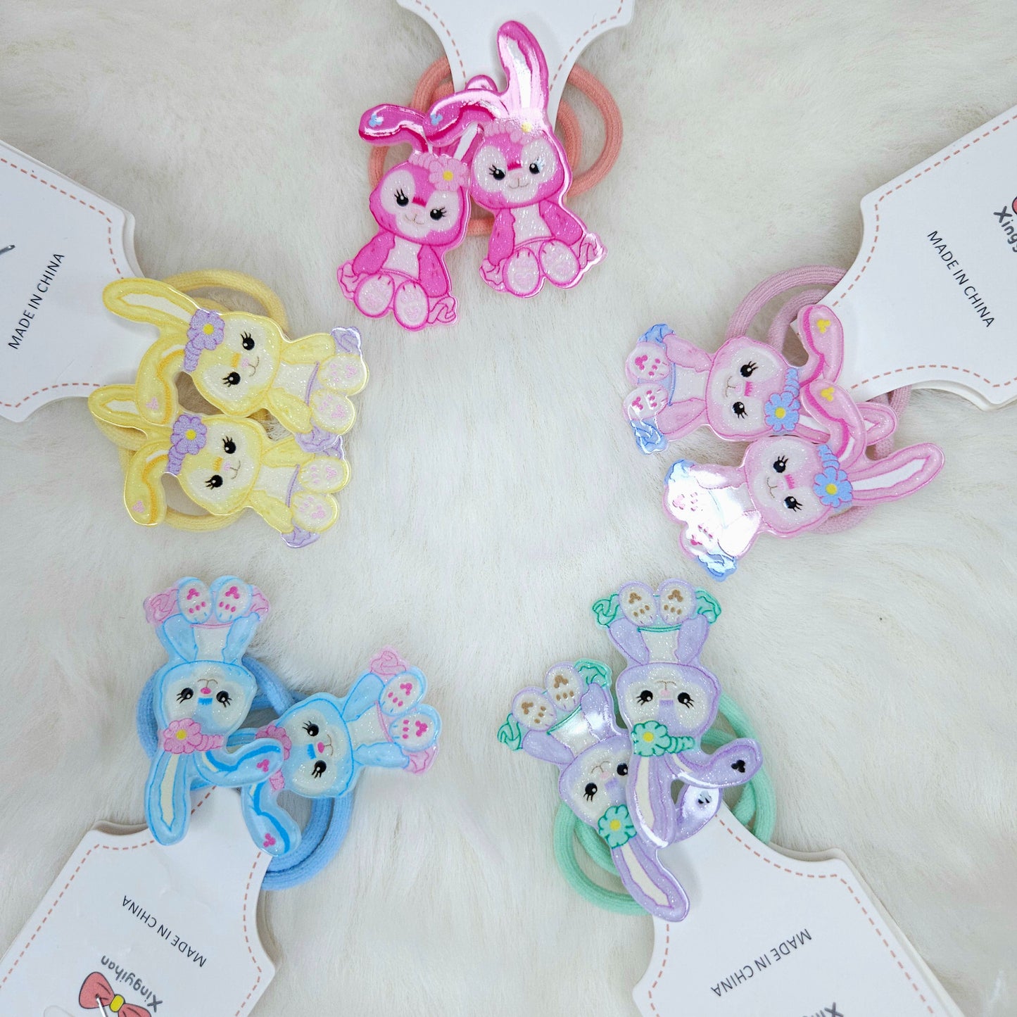 Set of colorful bunny-shaped hair ties on white background