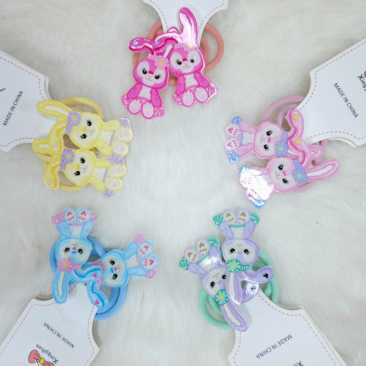 Set of colorful bunny-shaped hair ties on white background