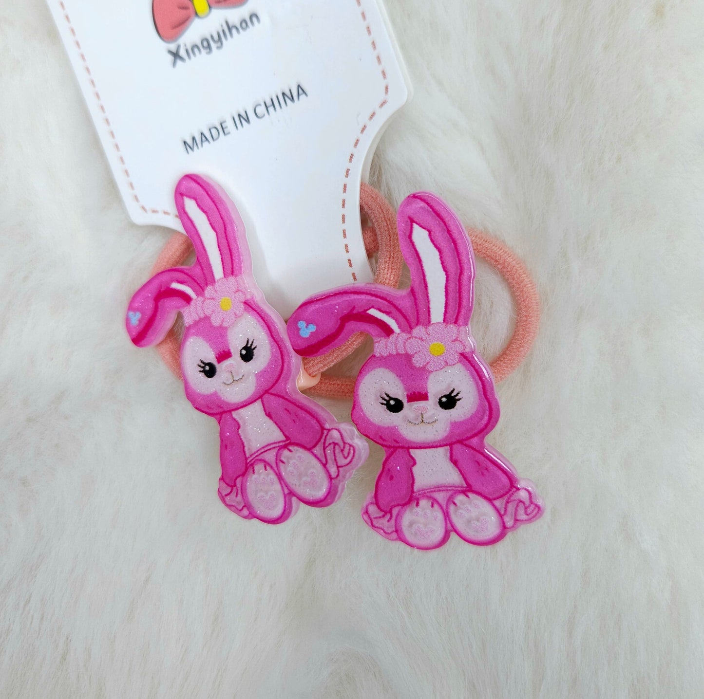 Two pink bunny-shaped hair ties with a visible brand tag on a white background