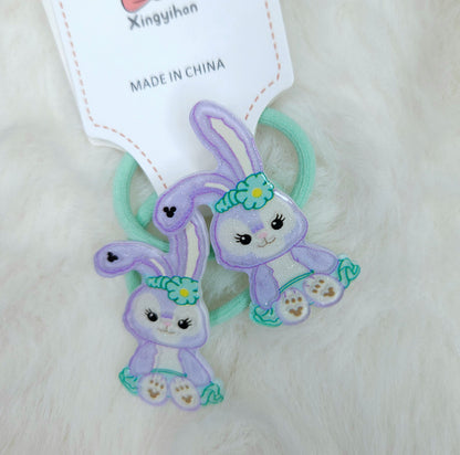 Two purple animal-shaped hair ties with green ribbons on a white background, accompanied by a 'Made in China' label.