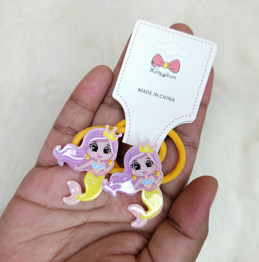 Two mermaid-shaped hair ties held by a hand with a 'Xingyihuan' branded card.
