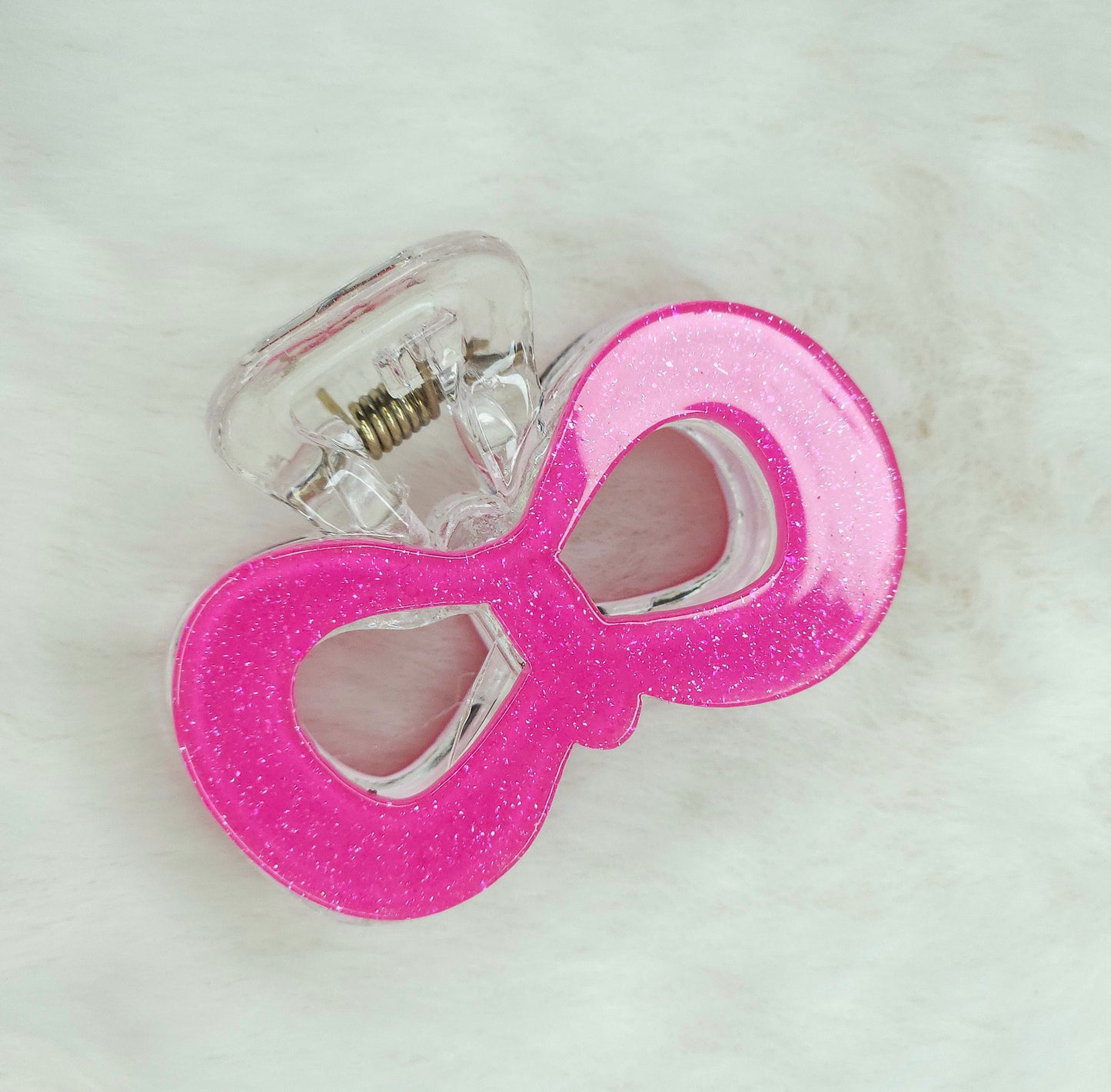 Pink glittery bow-shaped hair claw on a light background