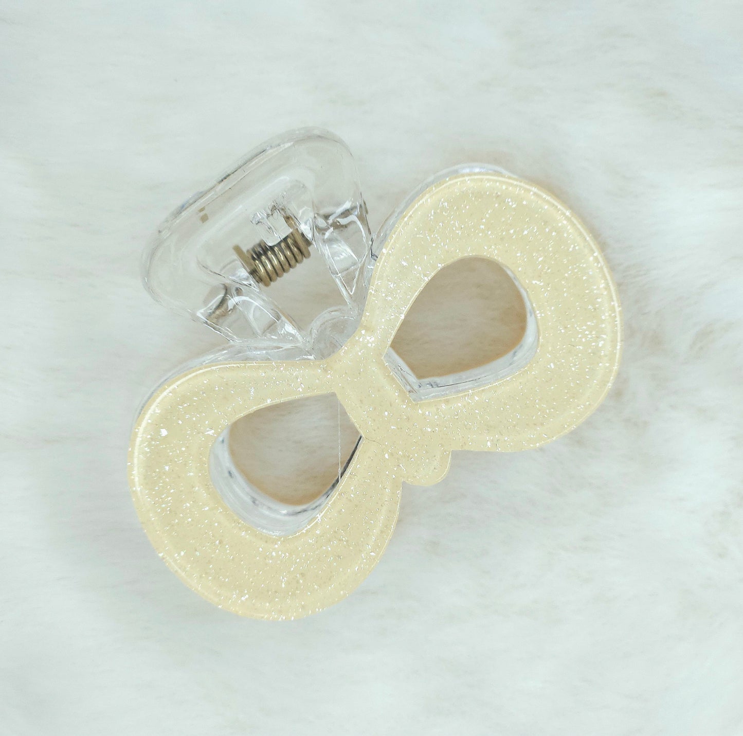 Light yellow glitter pop bow hair claw clip with sparkling finish, stylish and elegant accessory for securing hair.