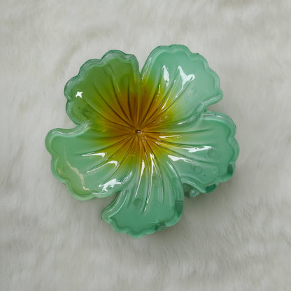 Green glass flower-shaped object on a light gray background