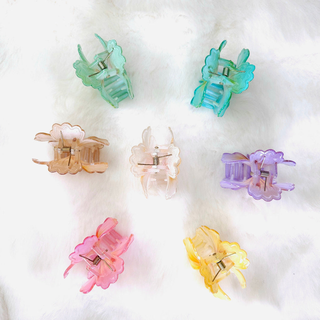 Set of seven translucent flower-shaped hair claw clips in colors including pink, purple, yellow, orange, mint green, and teal