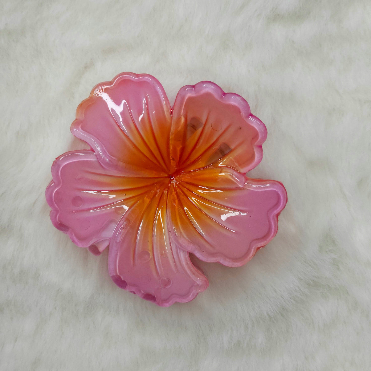 Pink and orange hibiscus flower-shaped hair claw clip on a white background