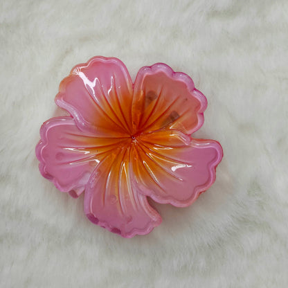 Pink and orange hibiscus flower-shaped hair claw clip on a white background