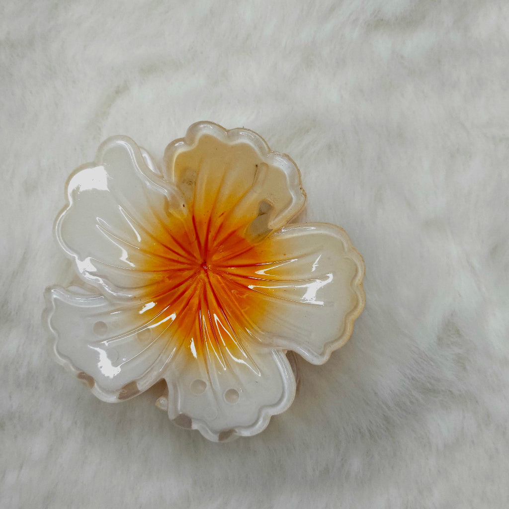 Decorative hair claw clip with a floral design on a textured white surface