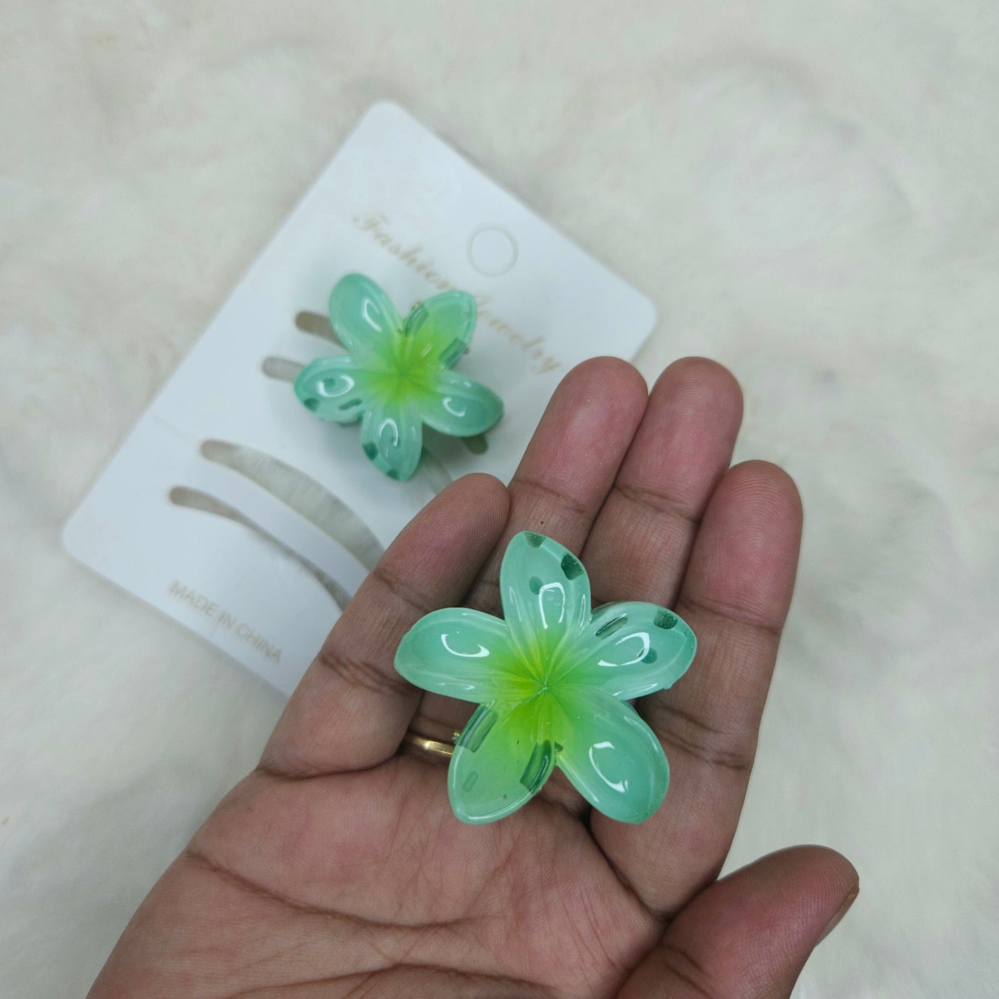 Green flower-shaped hair clips on a hand with a blurred background