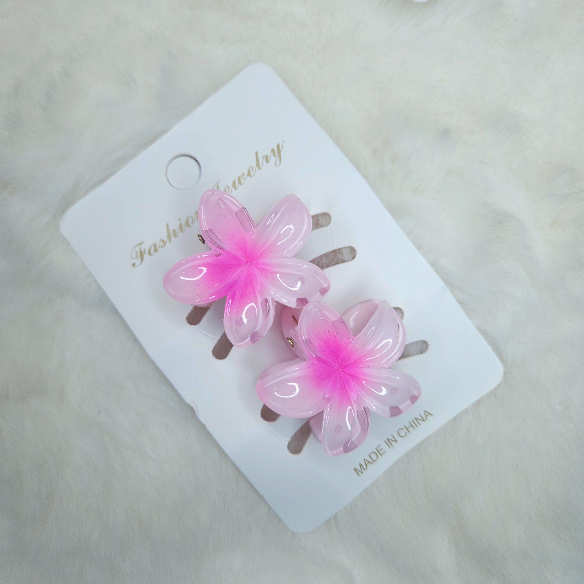 Pink flower-shaped hair clips on a white card with 'Fashion Jewelry' branding.
