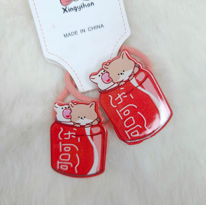 Two red cat-shaped hair ties with cartoon cats on a beige background, featuring a 'Made in China' label.