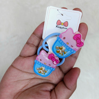 Two cartoon character hair ties on a hand with a brand card in the background.