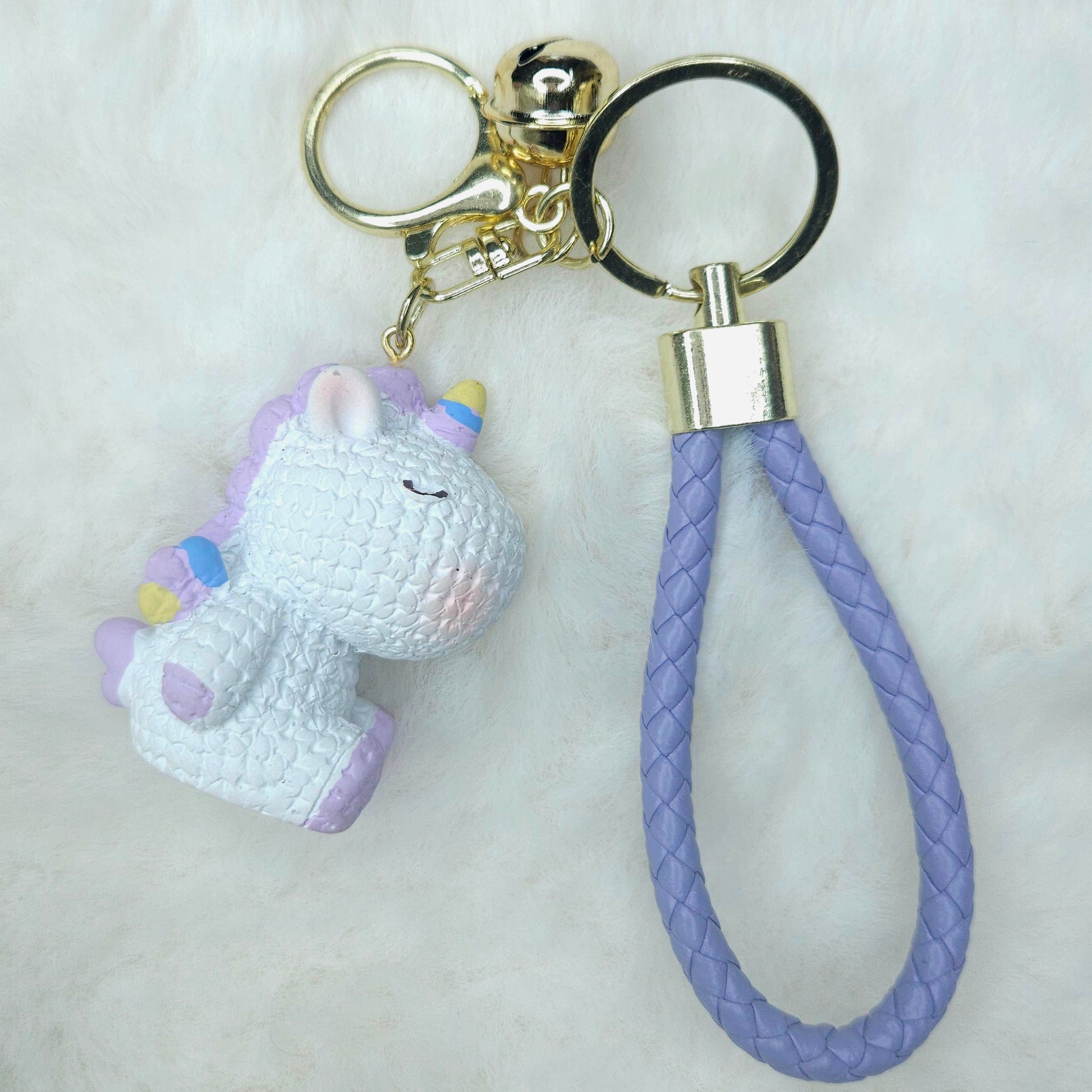 Keychain with a unicorn charm and purple braided rope on a white background