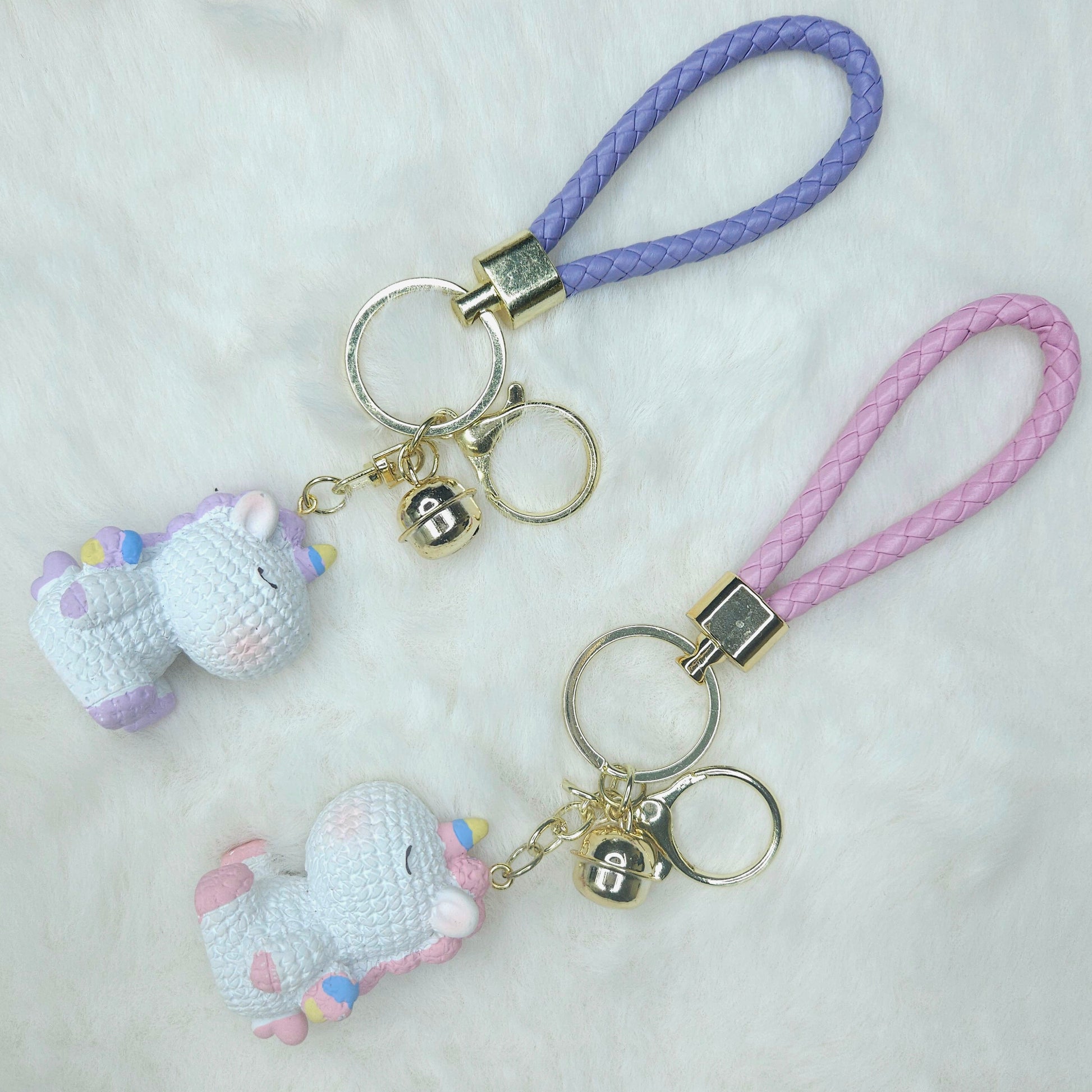 Two small unicorn keychains on a purple strap with a white background
