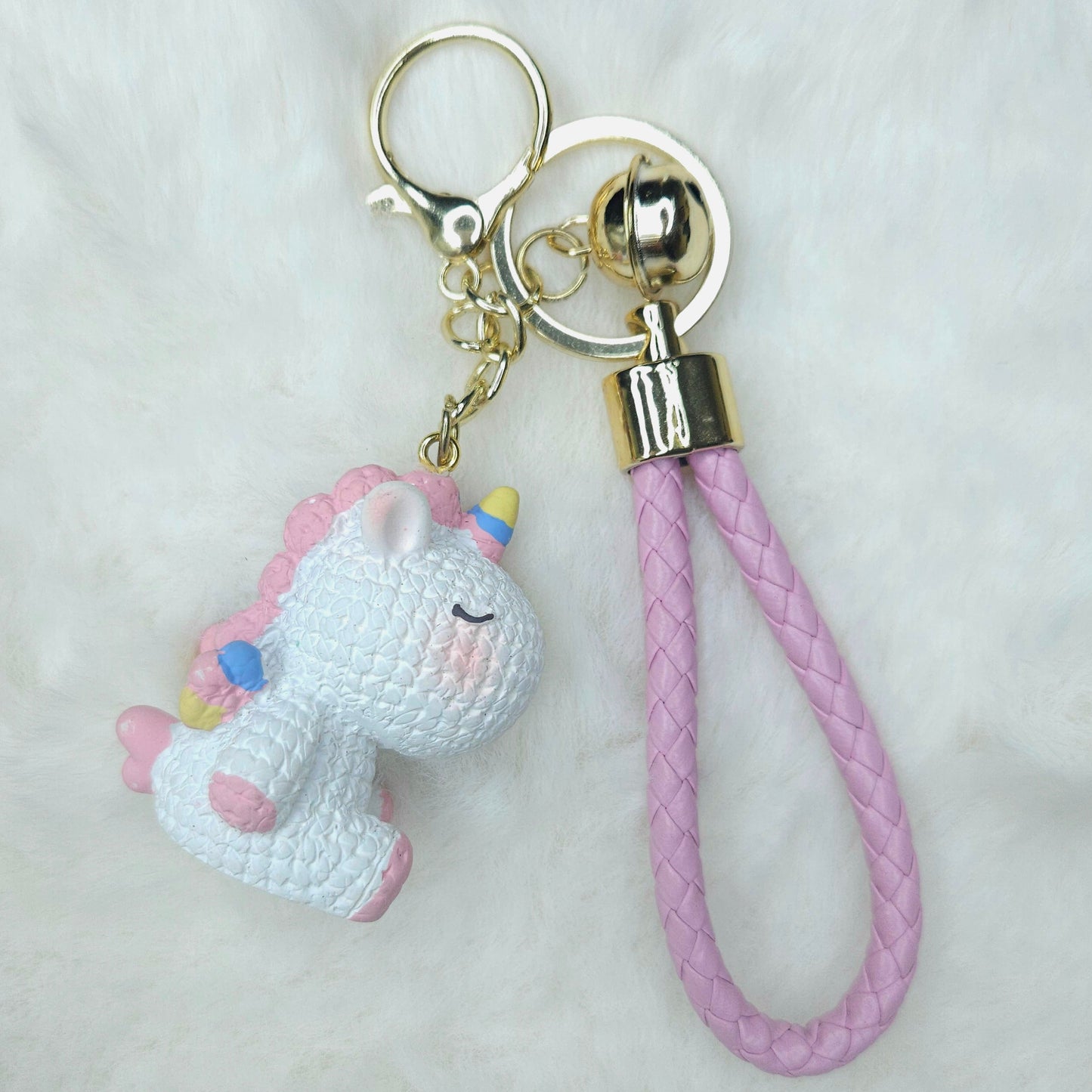 Keychain with a unicorn charm and pink braided strap on a white background