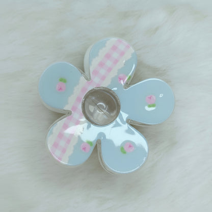 Close-up of floral-shaped hair claw featuring sky-blue gingham design and small rose accents.