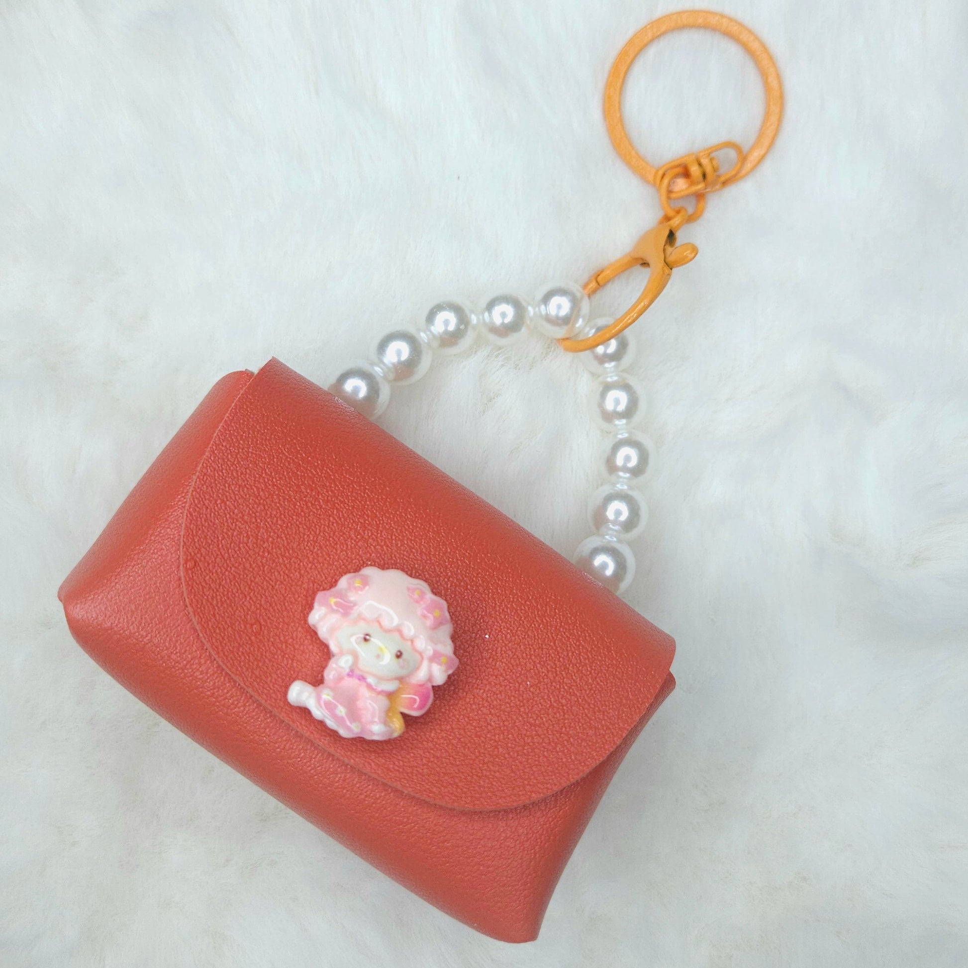 Pink keychain case with a floral charm on a white background