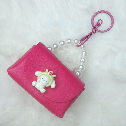 Pink wallet with a cartoon character charm and pearl necklace on a white background