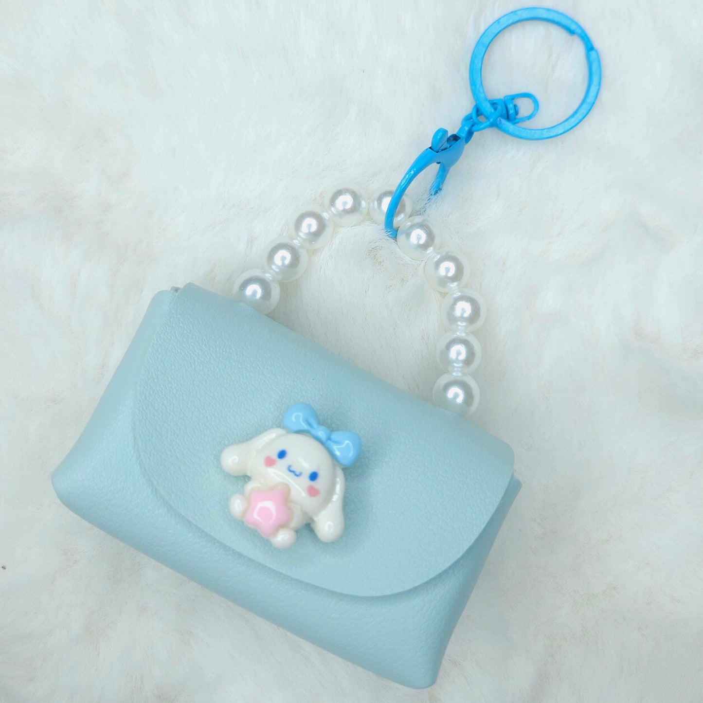 Light blue pouch with a cartoon character keychain on a white background