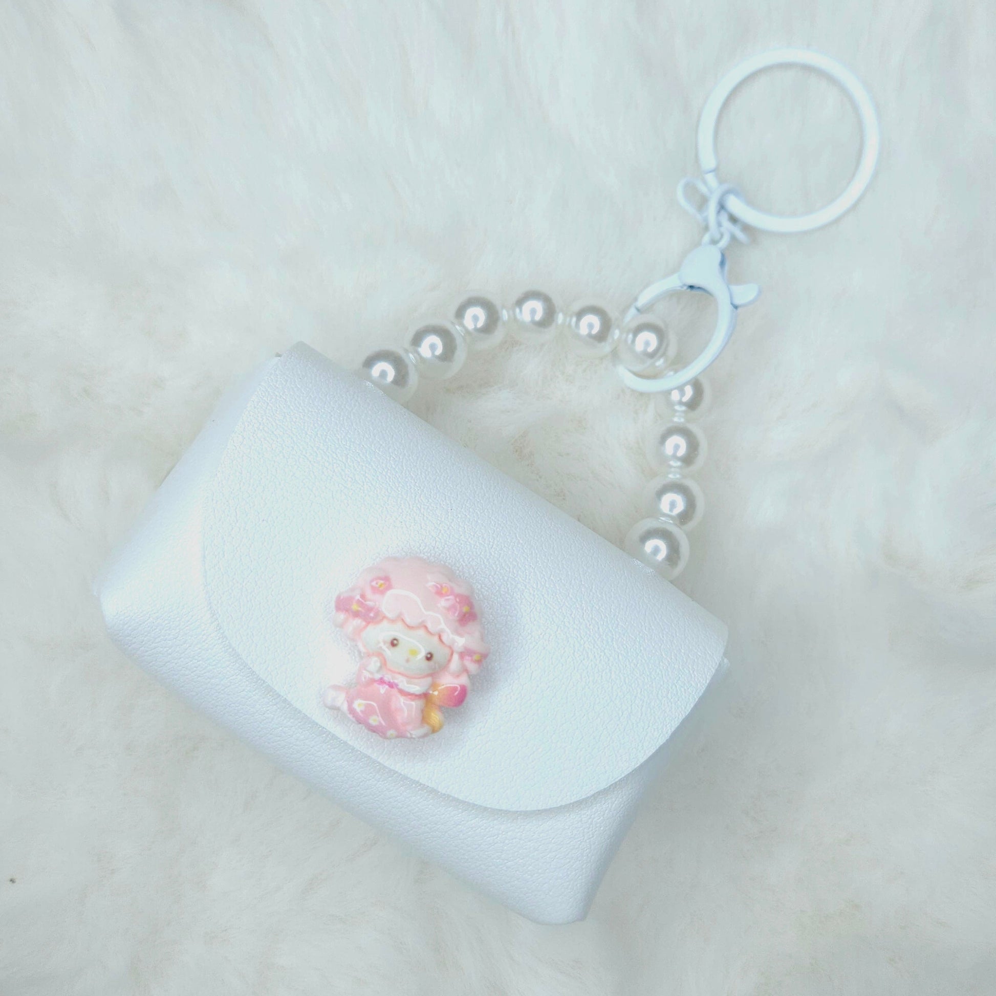 White pouch keychain with a pink sheep charm on a light gray background