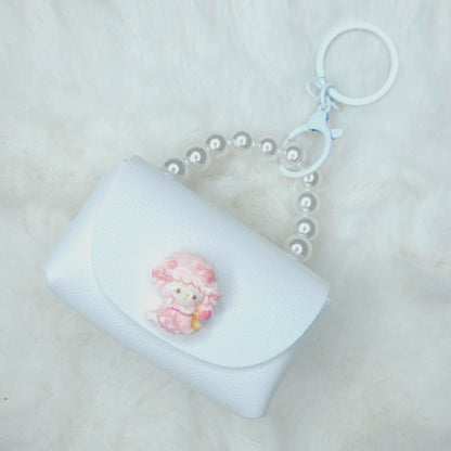 White pouch keychain with a pink sheep charm on a light gray background