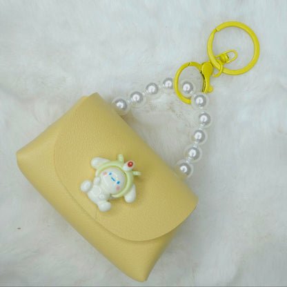 Yellow pouch with a keychain and bear charm on a white background