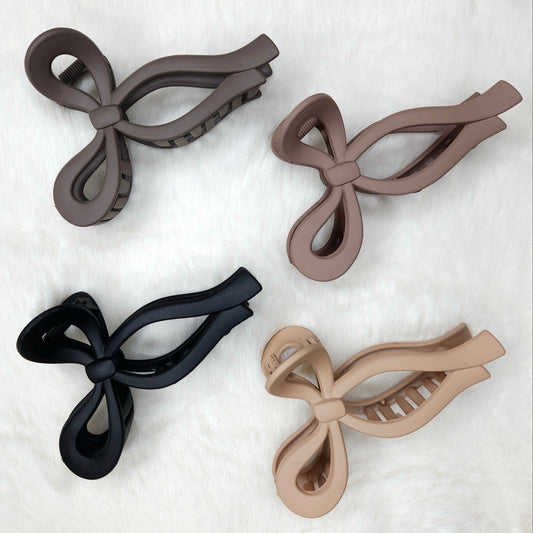 Four bow-shaped hair clips in black, brown, and beige on a white background