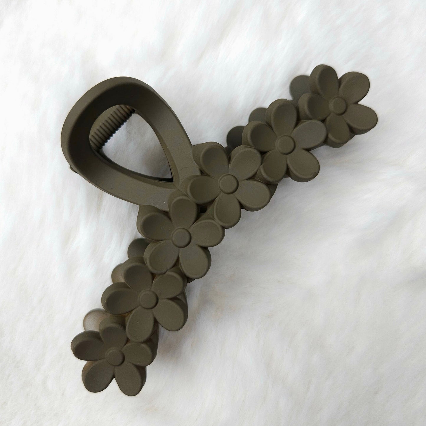 Dark brown textured hair clip with flower details on a white background