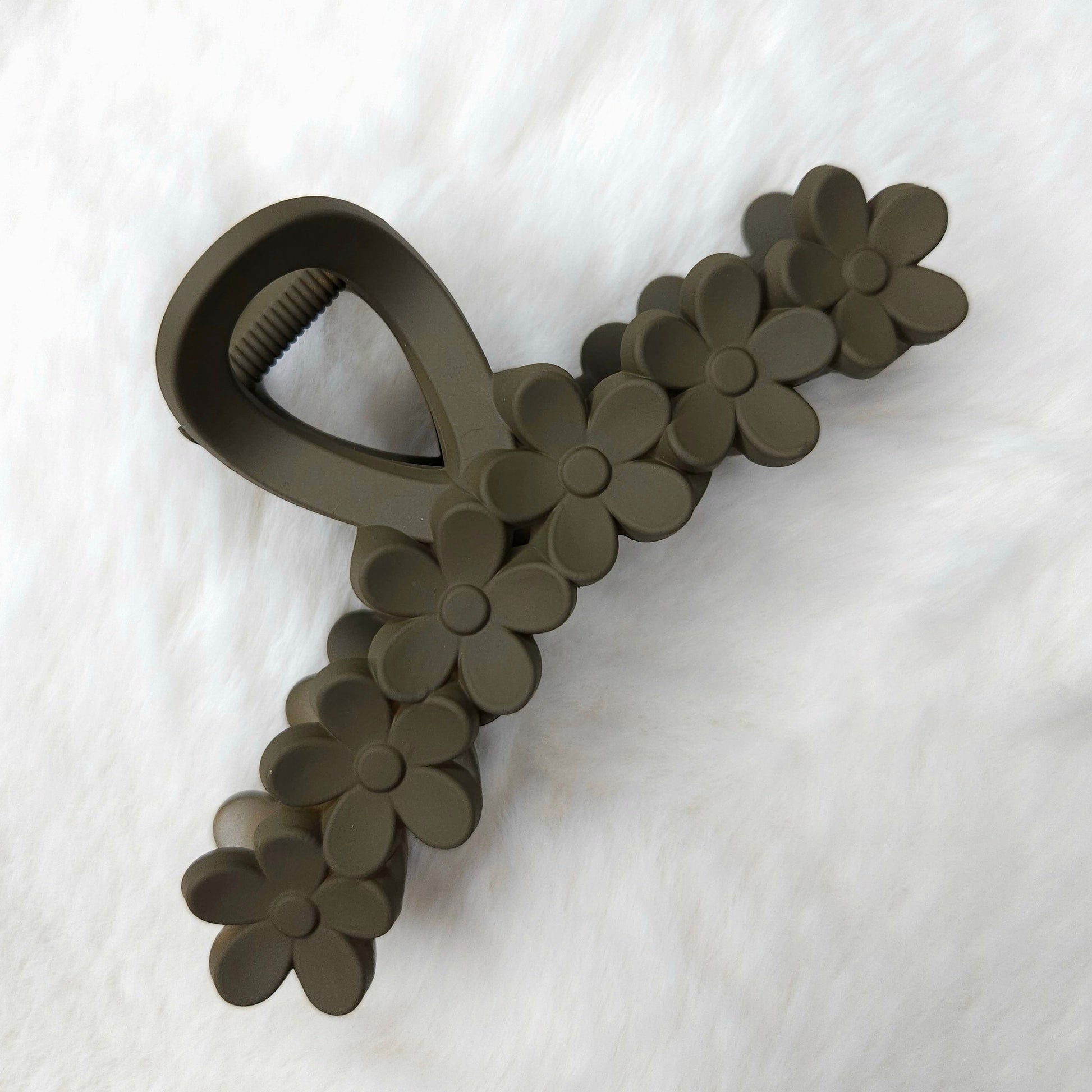 Dark brown textured hair clip with flower details on a white background