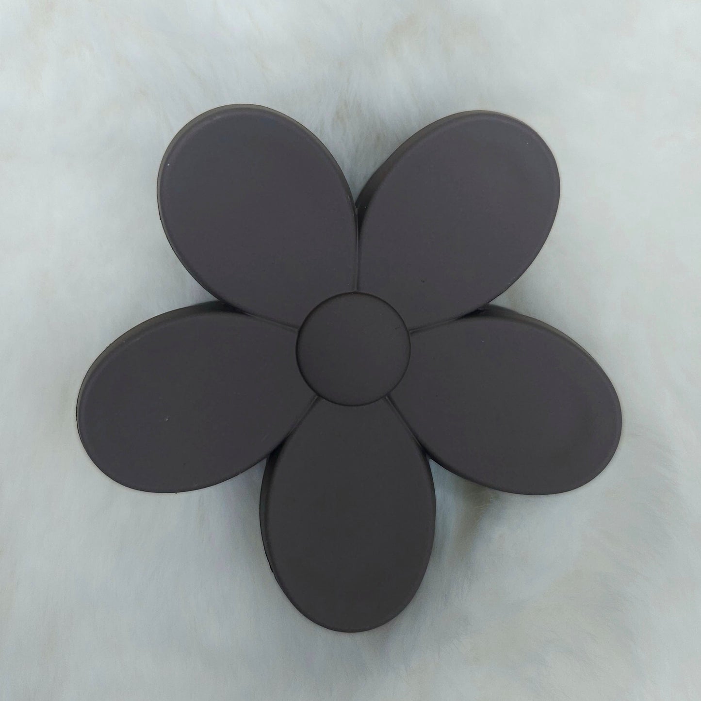 Black flower-shaped hair claw clip on a light gray background