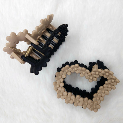Heart-shaped hair clip with black and beige design on a white background