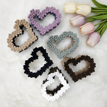 Set of heart-shaped hair claws in various colors on a white background